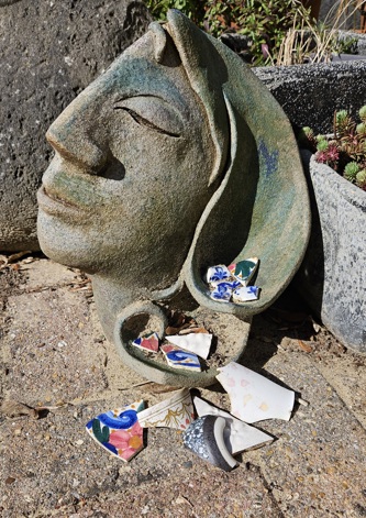 Slupture of a head with some broken china placed in the hair and ground in the foreground